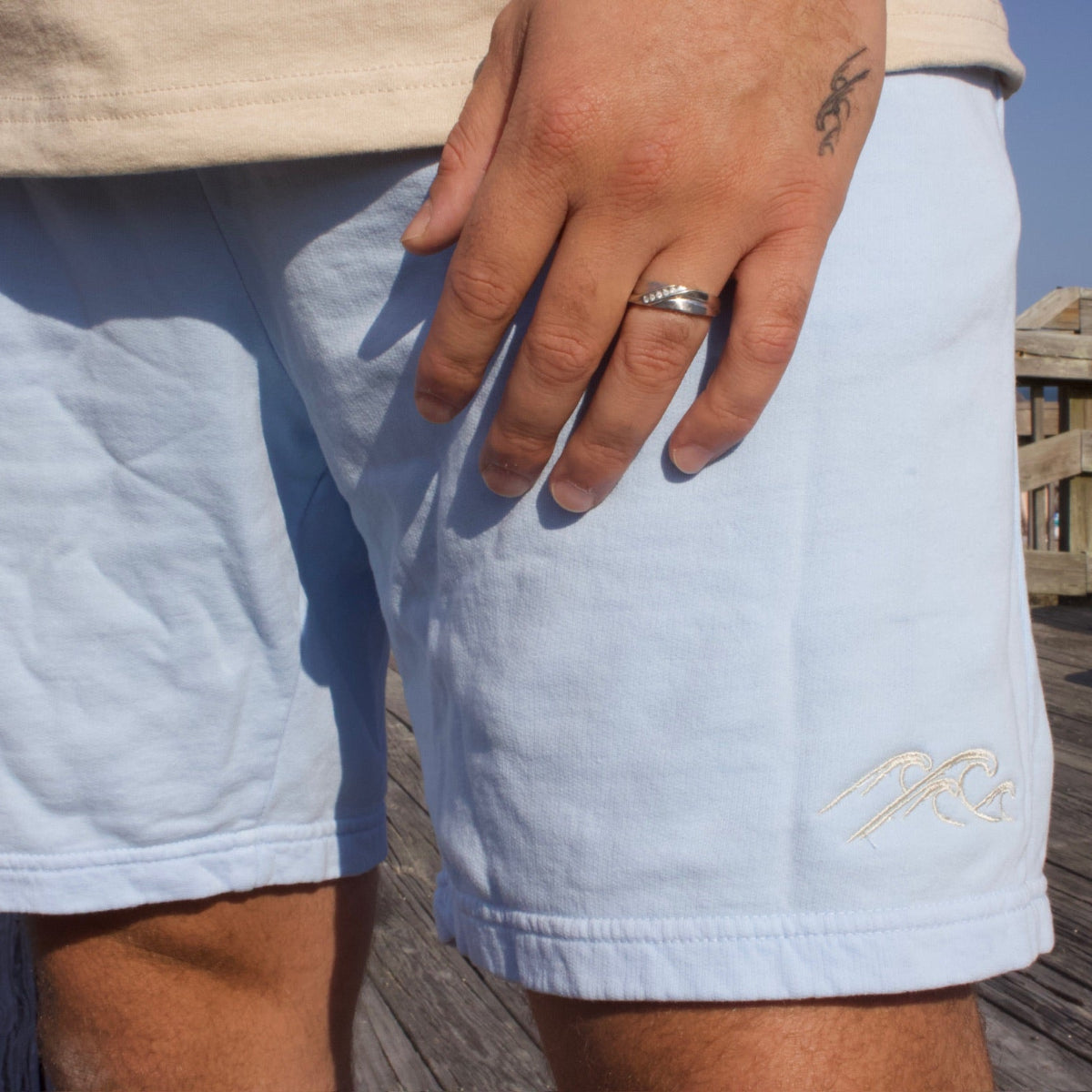 Person wearing light blue shorts with a brand logo on a wooden deck.
