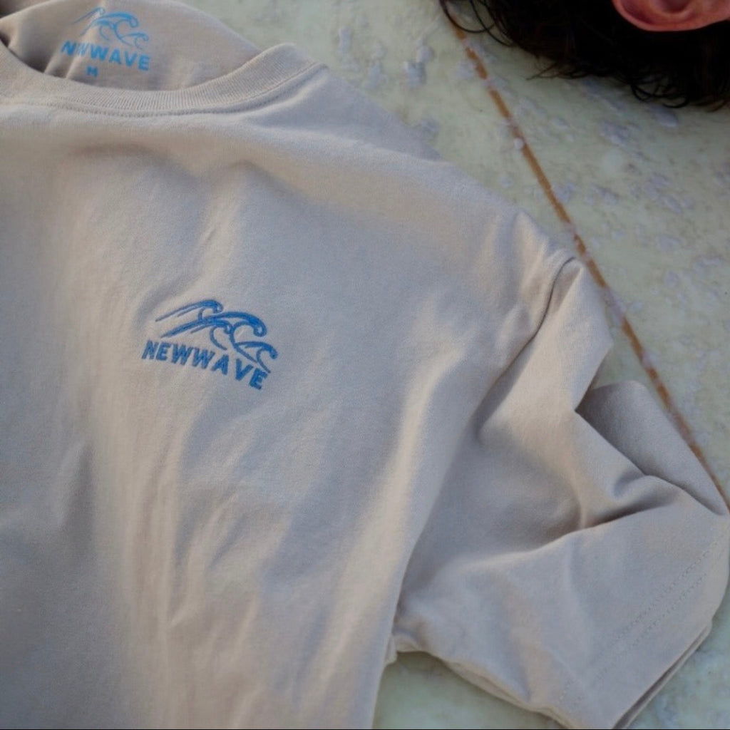 White shirt with blue 'Newwave' logo on a surf board