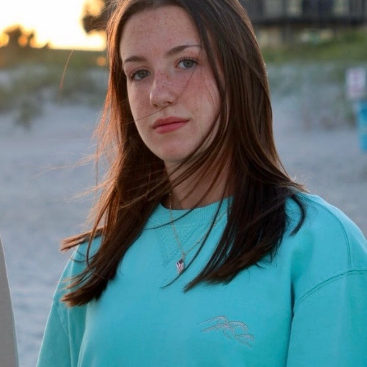 Woman wearing a teal shirt on a beach