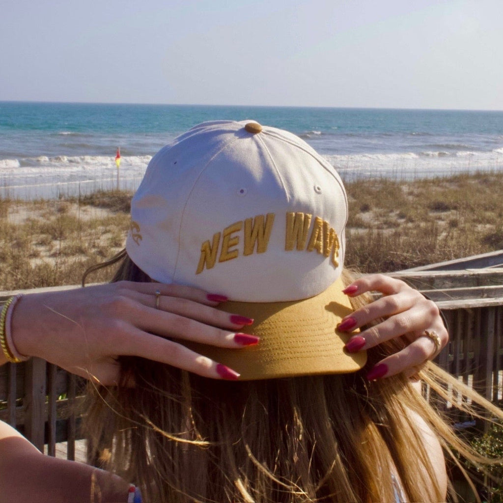 Person wearing a cap with 'New Wave' text at the beach